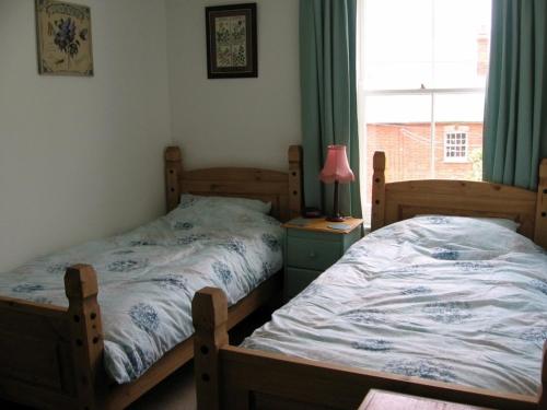 2 camas individuales en un dormitorio con ventana en Serenity House, en Glemsford