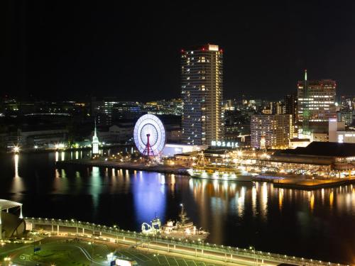 a city at night with a ferris wheel in the water at Hotel Okura Kobe in Kobe