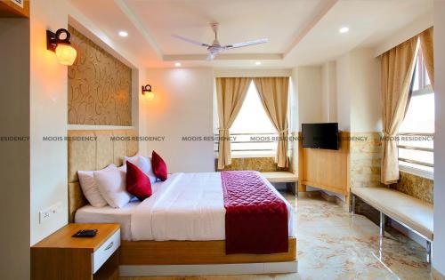 a bedroom with a bed and a tv and windows at Moois Residency in Kannur