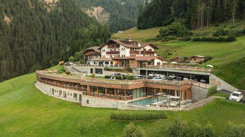 a large house on top of a green hill at Hotel Niblea Dolomites in Ortisei