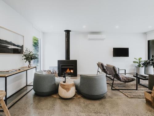 a living room with couches and a fireplace at Lithic House -wood fire and bush views in Hepburn Springs