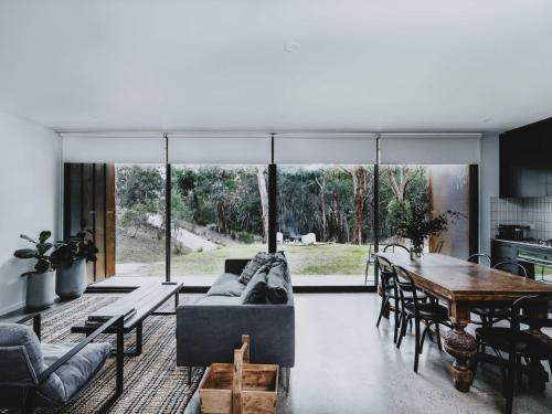 a living room with a couch and a table at Lithic House -wood fire and bush views in Hepburn Springs