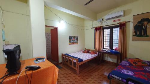 a bedroom with a bed and a desk and a tv at Ashavis Hotel Pvt Ltd in Māvelikara