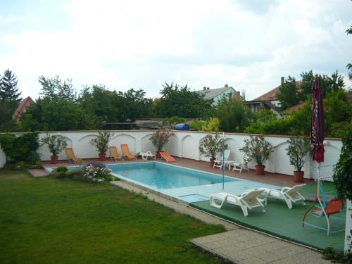 a swimming pool in a yard with chairs around it at Wellness Hotel Kakadu in Keszthely
