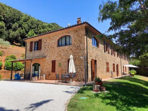 un grand bâtiment en briques avec une table et un parasol dans l'établissement Il Casolare Val Di Mare, à Riparbella