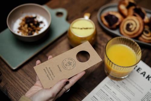 a person holding a piece of paper next to a table with breakfast foods at Stories Boutique Hotel in Budapest