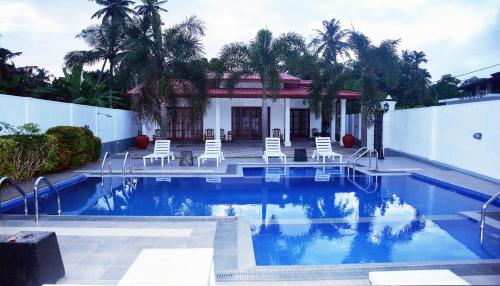 a swimming pool with chairs and a building at NEW SITHI VILLAS in Hikkaduwa