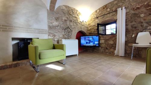sala de estar con silla verde y TV en La Casina de Piedra ENCANTO - Parte Antigua de Cáceres, en Cáceres