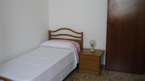 マリーナ・ディ・モーディカにあるCasa White Jasmineの小さなベッドルーム(ベッド1台、白いベッドカバー付きのナイトスタンド付)