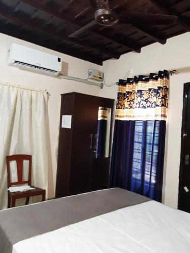 a bedroom with a bed and a chair and curtains at VALIYATH HOLIDAYS HOMESTAY in Munroe Island