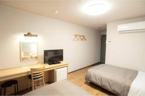 a bedroom with a desk with a bed and a bed and a deskictericter at Fujieda Ogawa Hotel フジエダオガワホテル in Fujieda