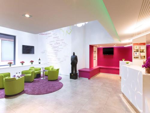 a waiting room with green chairs and a mannequin at Ibis Styles Madrid Prado in Madrid