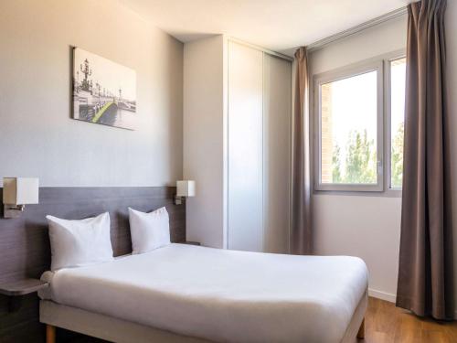 um quarto com uma cama grande e uma janela em Aparthotel Adagio Access Nogent sur Marne em Nogent-sur-Marne