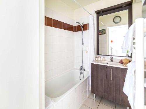 a bathroom with a tub and a sink and a mirror at Aparthotel Adagio Access Orléans in Orléans