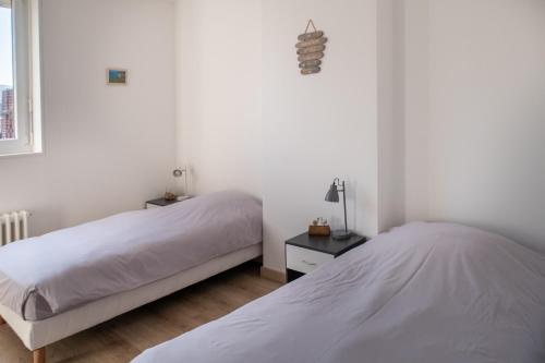 twee bedden in een slaapkamer met witte muren bij La mature in Fécamp