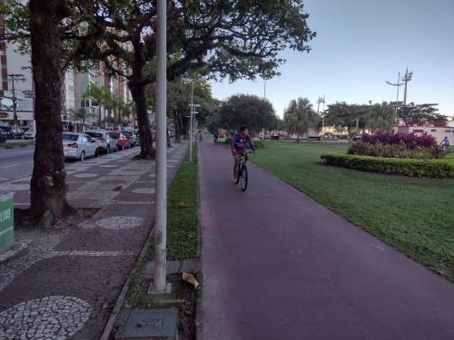 a person riding a bike down a sidewalk at Hotel e Pousada das Goianas in Santos
