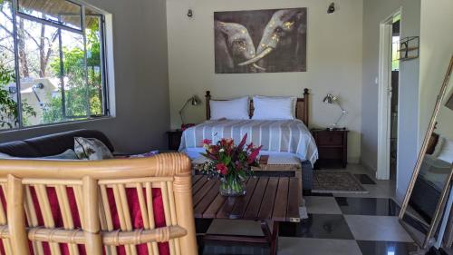 a bedroom with a bed and a table with flowers on it at Sunbirds Cottage in Kasane