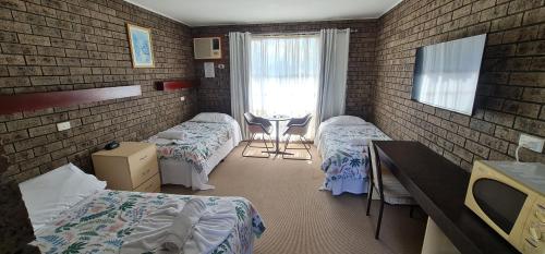 um quarto de hospital com duas camas e uma mesa em The SIM - Sussex Inlet Motel em Sussex inlet