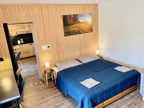 a bedroom with a blue bed and a kitchen at Apartmán u jezera Lipno - Nové in Nová Pec