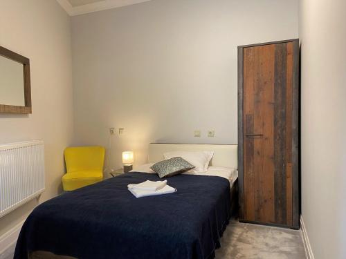 a bedroom with a bed and a yellow chair at Maisonette Apartments in Cîmpulung