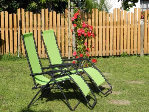 deux chaises vertes assises dans l'herbe devant une clôture dans l'établissement Auelehof, à Laives