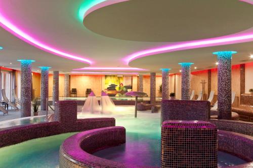 a hotel lobby with purple chairs and a pool at Tó Wellness Hotel in Bánk