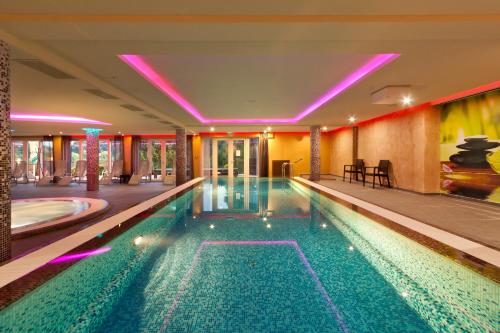 a swimming pool in a hotel with purple lights at Tó Wellness Hotel in Bánk