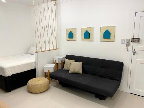 a living room with a black couch and a bed at Studio moderno na avenida da praia - Boqueirão in Santos