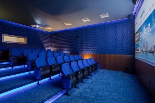 a cinema room with blue chairs and a screen at Granada Luxury Belek - Family Kids Concept in Belek