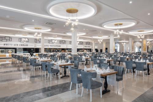 a dining room with tables and chairs and chandeliers at Granada Luxury Belek - Family Kids Concept in Belek