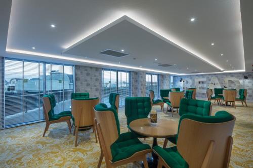a waiting room with green chairs and tables and windows at Granada Luxury Belek - Family Kids Concept in Belek