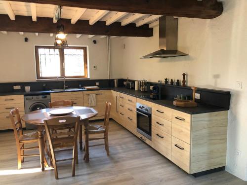 a kitchen with a table and a dining room at Havre de paix et de verdure proche Walibi et A43 - 4 étoiles in Corbelin