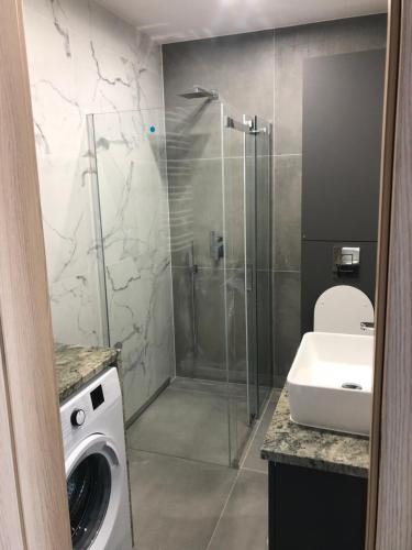 a bathroom with a shower and a sink and a washing machine at Apartamenty Platinex 5 in Kraków