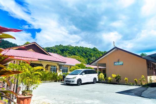 a white car parked in front of a building at NR Langkawi Motel in Pantai Cenang