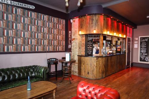 a bar with a green leather couch and a bartender at Suncliff Hotel - OCEANA COLLECTION in Bournemouth