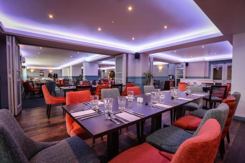 a dining room with tables and chairs with wine glasses at Suncliff Hotel - OCEANA COLLECTION in Bournemouth