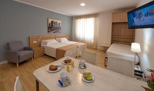 a room with a bed and a table with food on it at Hotel Apartamentos Dabarca in Pontevedra