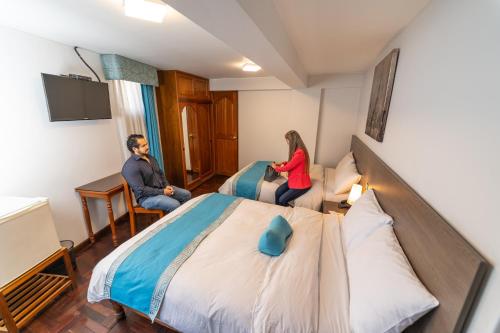a man and woman sitting on a bed in a hotel room at Samana Hotel in Arequipa