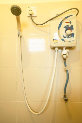 a shower with a hose attached to a wall at NR Langkawi Motel in Pantai Cenang
