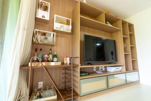 a living room with a tv and a shelf with bottles at Residencial Ykutiba- Imbassaì Ap A-103 in Imbassai