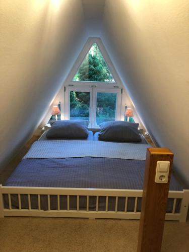 Bett in einem Zimmer mit Fenster in der Unterkunft Ferienhaus Reetdach 1300qm Privatgrundstück Bootssteg Sauna Templin Lübbesee Uckermark Erholung pur Seenplatte in Petersdorf