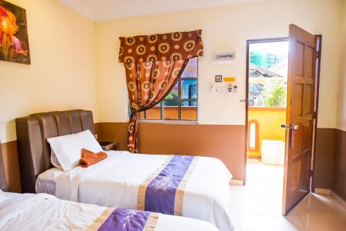 a hotel room with two beds and a window at NR Langkawi Motel in Pantai Cenang
