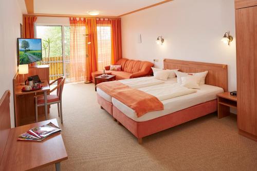 a bedroom with a bed and a living room at Land- und Aktivhotel Altmühlaue in Bad Rodach
