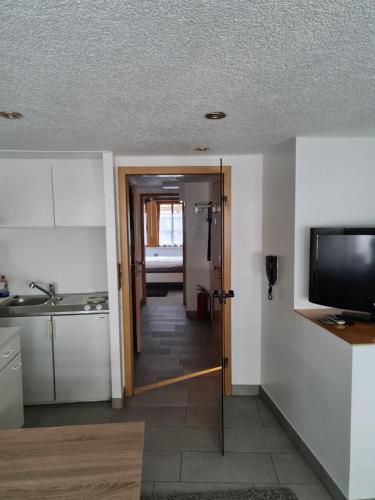 a kitchen with a door open to a kitchen with a television at FeWo Iris in Alsfeld