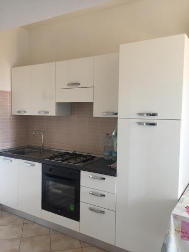 een witte keuken met een fornuis en een koelkast bij Ginepro family in Valledoria