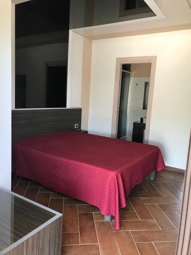 a bed in a room with a red blanket on it at B&B & VITA in Mirto