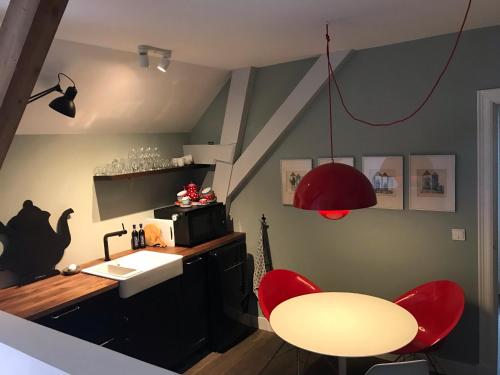 uma cozinha com cadeiras vermelhas, uma mesa e um lavatório em B&B Logeren bij de burgemeester em Stad aan ʼt Haringvliet