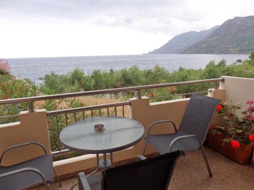 a table and chairs on a balcony overlooking the water at Ravdoucha Beach Studios in Ravdhoúkha