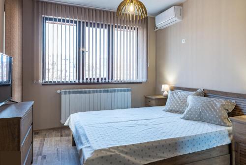 a bedroom with a bed and a large window at Apartment Trayana in Stara Zagora