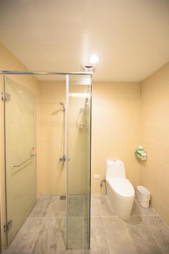 a bathroom with a toilet and a glass shower stall at 松柏文旅Cypress Inn in Taitung City